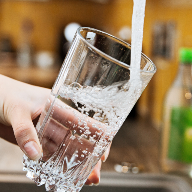 Une personne se sert un verre d'eau au robinet.